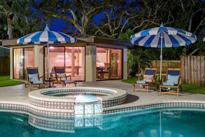 Un área de piscina con jacuzzi, sillas de descanso y sombrillas.