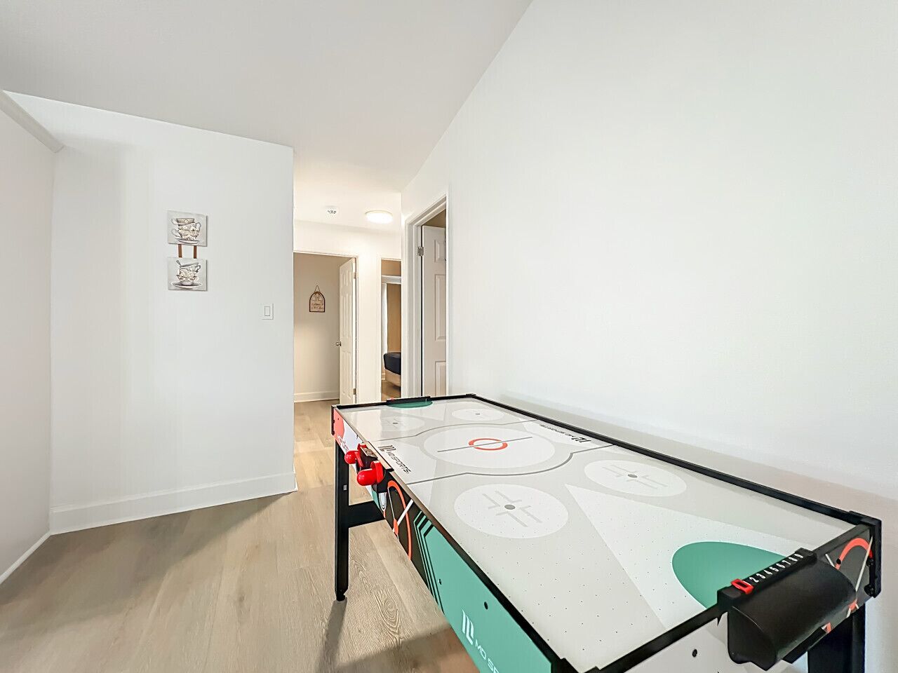 A room with a foosball table, a door, and a hallway leading to another room.