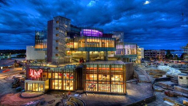 A modern multi-story building with a glass facade, a prominent 'JUMP' sign, and a construction site nearby. - 3BR Family Meridian Home ★Sleeps 6 ★ 5 Min to The Village ★ Indoor–Outdoor Patio (Meridian)