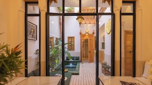 A modern interior with a glass partition, a wooden staircase, and a cozy seating area with a green sofa and a small table. - Riad Jardin d'Orient - Riad with 2 pools in the heart of the Medina (Marrakech)