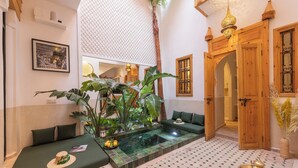 A hotel lobby with a seating area, a small indoor water feature, and a reception desk. - Riad Jardin d'Orient - Riad with 2 pools in the heart of the Medina (Marrakech)