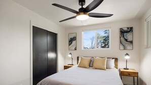 A bedroom with a bed, two bedside tables, a ceiling fan, and abstract wall art. - Downtown Ebony- 1.5 Miles from Whiskey Row (Prescott)