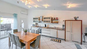 A modern kitchen with white cabinets, a wooden dining table, and a large window. - 4 bedroom gorgeous home in Saint Raphael (Saint Raphael)