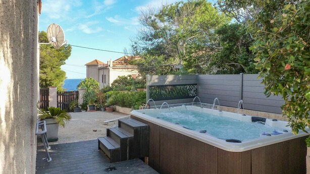 A hot tub with a wooden deck and steps leading up to it, surrounded by greenery and a view of the sea. - 4 bedroom gorgeous home in Saint Raphael (Saint Raphael)
