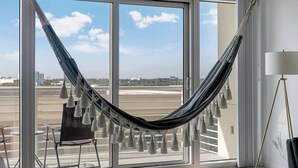 A hammock hanging by a window with a view of a cityscape. - Midtown Miami Marvel- Heated Pool & Prime Location (Miami)