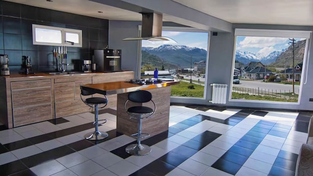 Une cuisine moderne avec un coin bar, de grandes fenêtres offrant une vue sur les montagnes et un sol à carreaux.