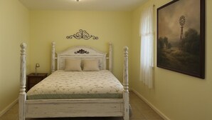 A bedroom with a four-poster bed, a nightstand, a lamp, and a landscape painting on the wall. - Peaceful 1-bed studio cottage in Gering perfect for relaxing stay (Gering)