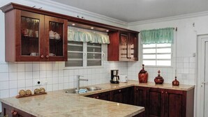 Une cuisine avec des meubles en bois, un plan de travail en granit, une fenêtre avec un rideau et un évier.