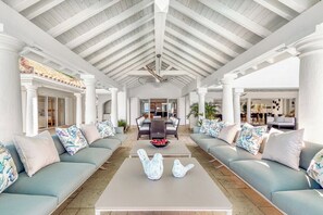 A spacious indoor area with a high ceiling, light-colored walls, and a central seating area with sofas and a coffee table. - Petite Plage 5   Exclusive Beachfront Villa (Philipsburg)