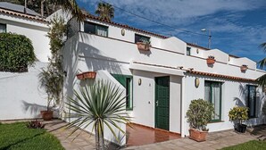 A white building with green shutters, a tiled roof, and potted plants. - Apartments inside of banana plantation with ocean view Terrazas Malpaís (Garachico)