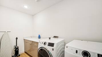 Une buanderie équipée d’un lave-linge, d’un sèche-linge et d’un aspirateur.