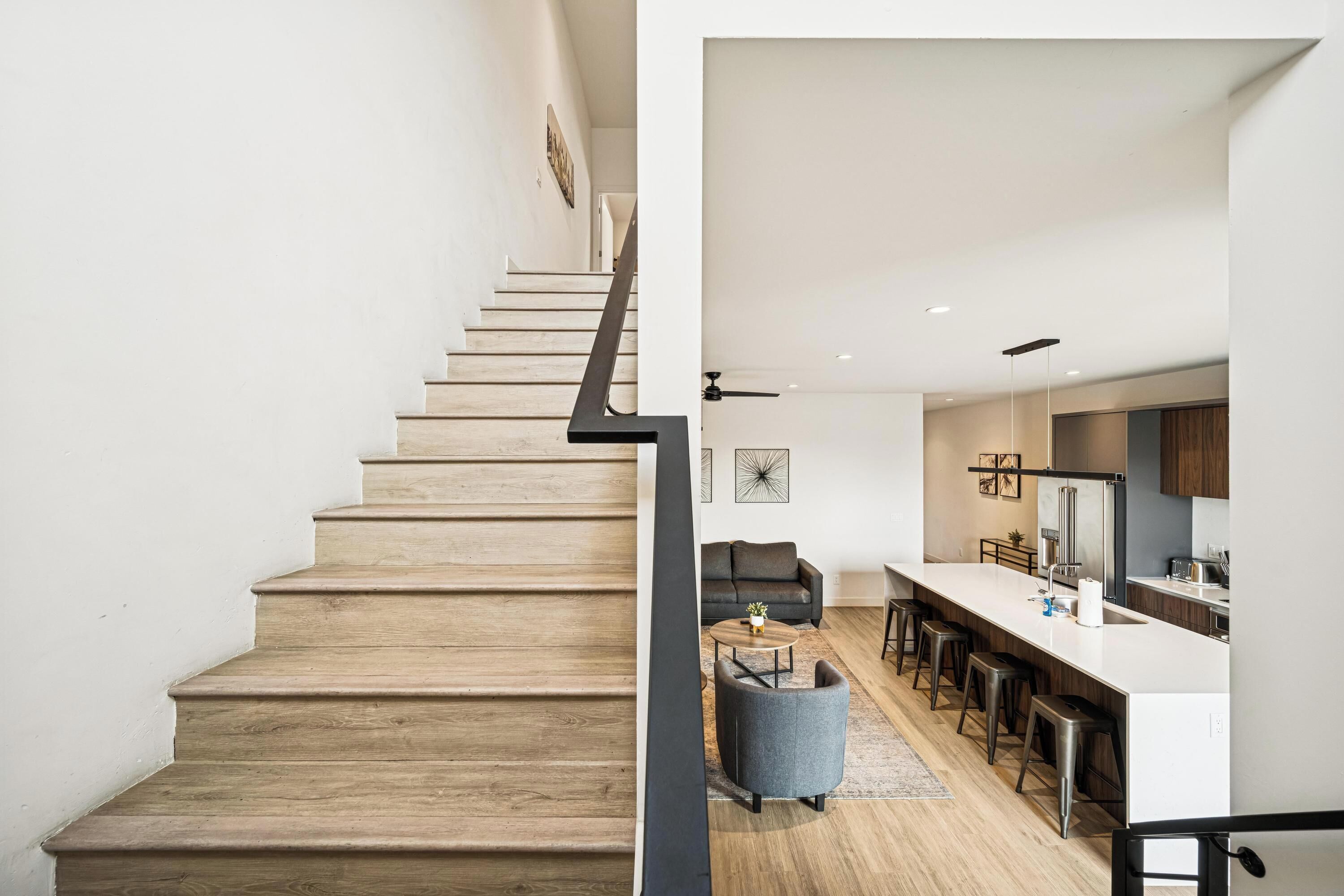 A modern kitchen with a central island, bar stools, and a dining area.