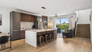 A modern kitchen with a central island, bar stools, and a dining area with a table and chairs. - The Dune Lofts (Scottsdale)