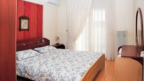 A bedroom with a bed, a nightstand, a mirror, and a radiator. - Central Grevena Retreat With Mountain Views (Grevena)