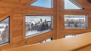 Un intérieur en bois doté de nombreuses fenêtres donnant sur un paysage enneigé et des arbres.