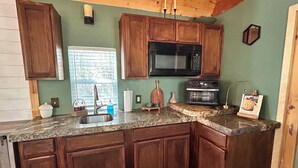 A kitchen with wooden cabinets, a granite countertop, a microwave, and a toaster. - Adorable 1-bedroom Casita with AC in welcoming Lakeside (Lakeside)