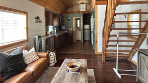 A spacious living area with a wooden ceiling, a ceiling fan, a kitchen with a refrigerator, and a staircase. - Adorable 1-bedroom Casita with AC in welcoming Lakeside (Lakeside)