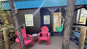 A wooden cabin with two red chairs and a hammock on a deck. - Adorable 1-bedroom Casita with AC in welcoming Lakeside (Lakeside)