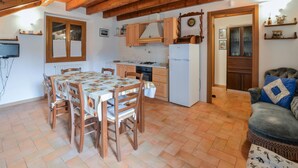 Een gezellige keuken met houten kastjes, een eettafel met stoelen en een kleine koelkast.