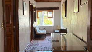 A hallway with a glass-top table, wooden beams, a patterned rug, and a window with a view of greenery. - Calli Yoloiztac, Valle de bravo (Valle de Bravo)
