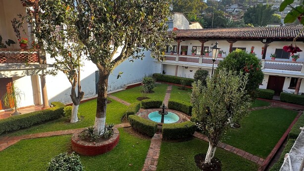 A courtyard with a fountain, neatly trimmed hedges, and a building with a tiled roof. - Calli Yoloiztac, Valle de bravo (Valle de Bravo)
