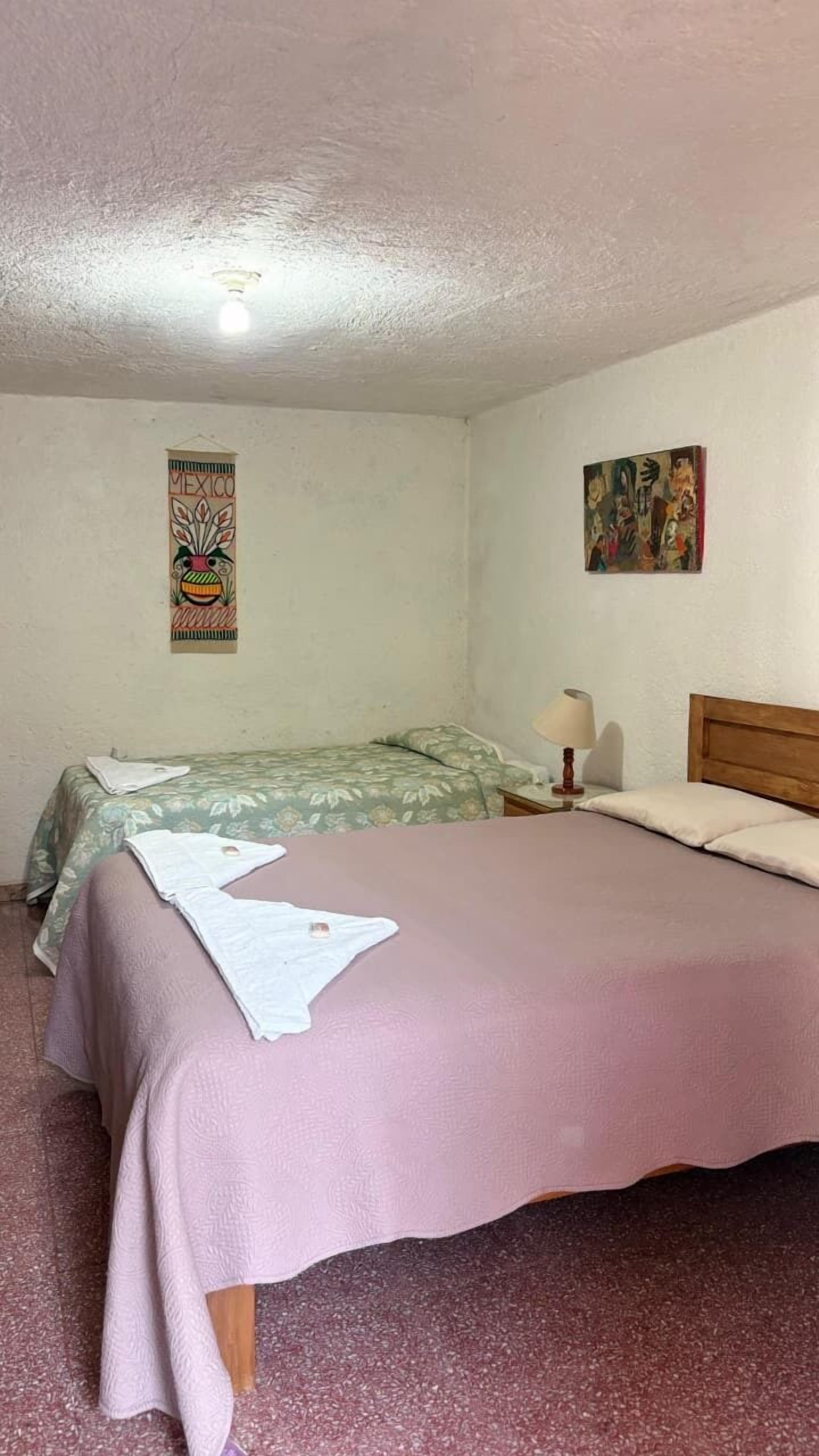 Ein Schlafzimmer mit zwei Betten, einer Wanddekoration und einem Gemälde.