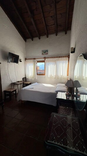 A bedroom with a bed, bedside tables, a desk, a chair, a television, and a window with curtains. - Calli Yoloiztac, Valle de bravo (Valle de Bravo)