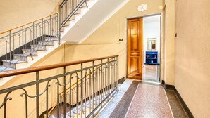 A staircase with a wooden handrail and metal balusters, leading to a room with a wooden door and a blue cabinet. - 1 bedroom nice apartment in Genova (Genova)