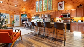 A cabin interior with a dining area, kitchen, and a fireplace. - The Great Smoky Haven (Sevierville)