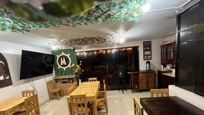 A dining area with wooden furniture, a TV mounted on the wall, and decorative plants. - hostal milagros (Chancay)