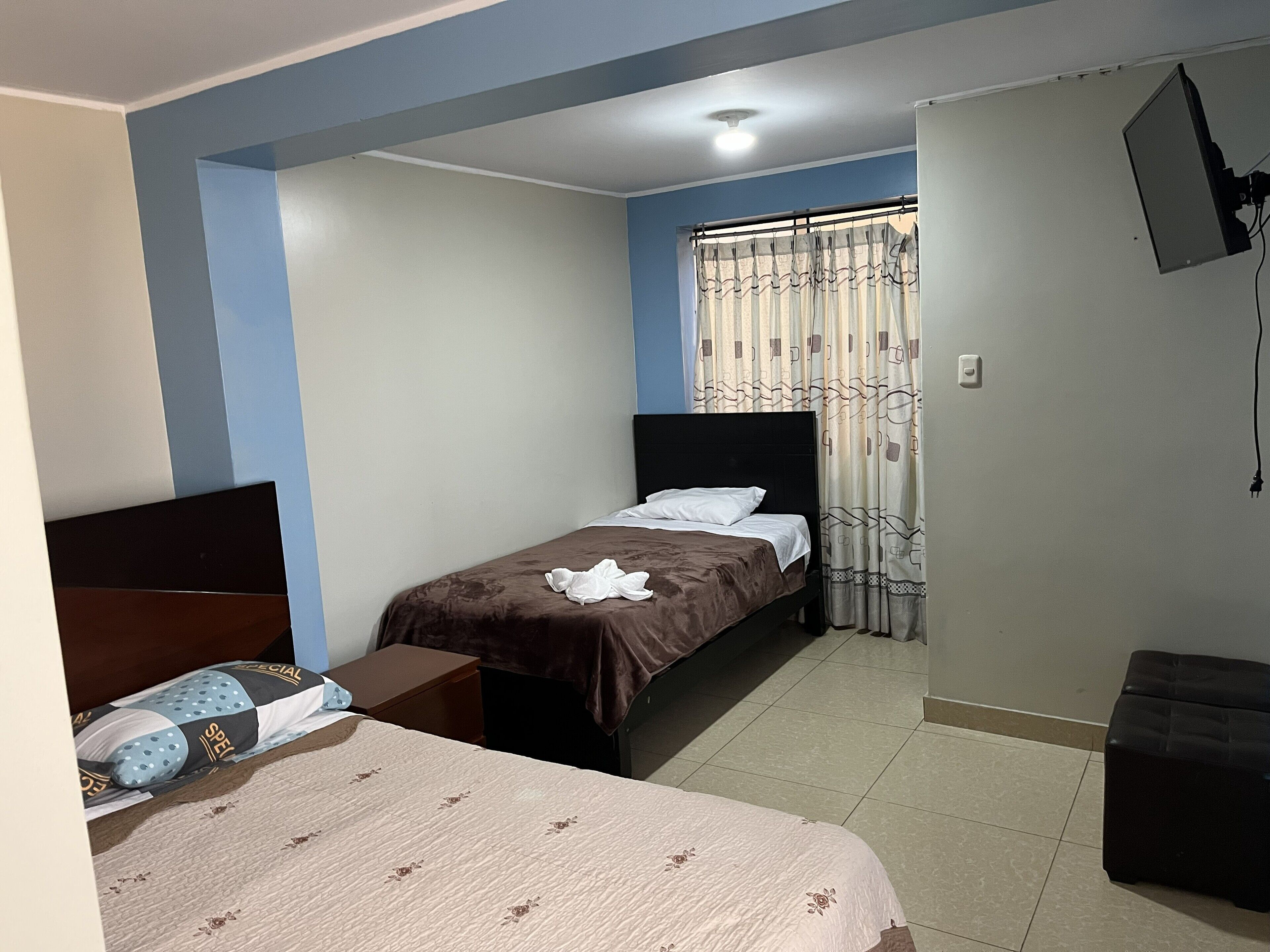 A bedroom with a bed, a bedside table, a wardrobe, and a TV mounted on the wall.
