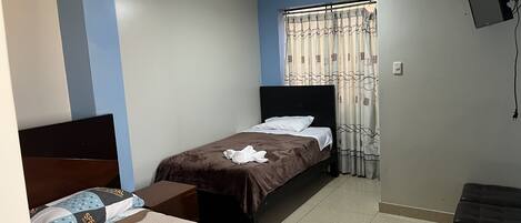 A bedroom with a bed, a bedside table, a wardrobe, and a TV mounted on the wall.