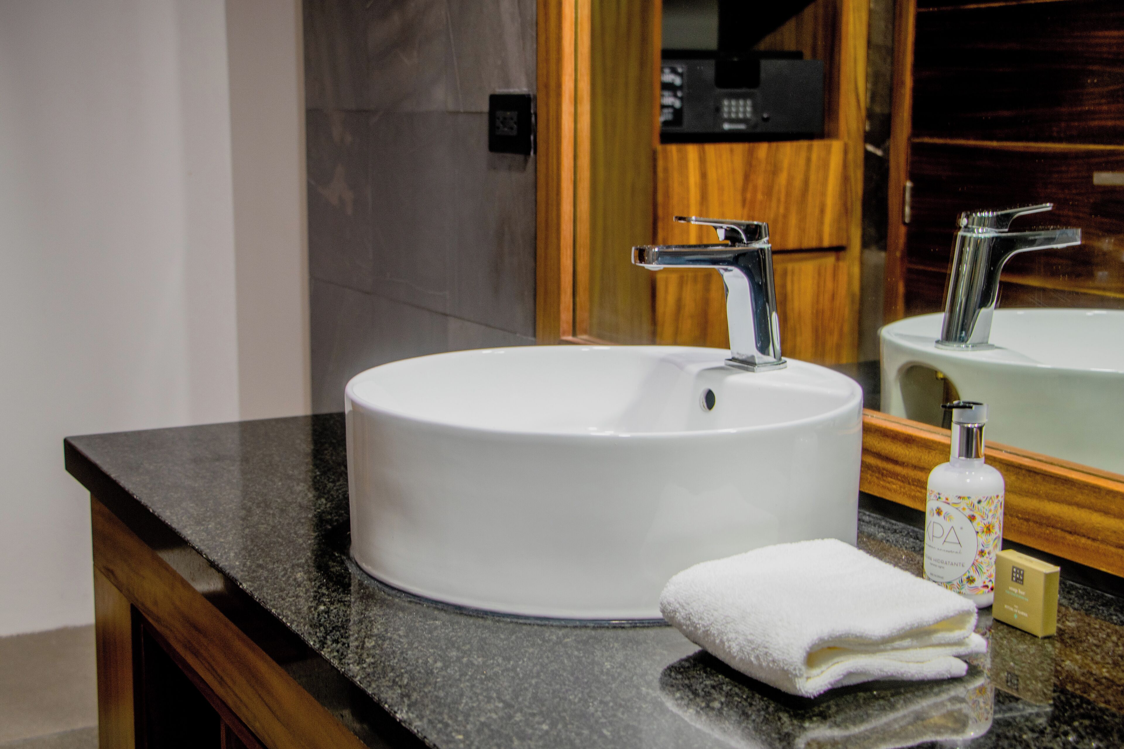 Un baño con un lavabo blanco, un espejo y una toalla en la encimera.