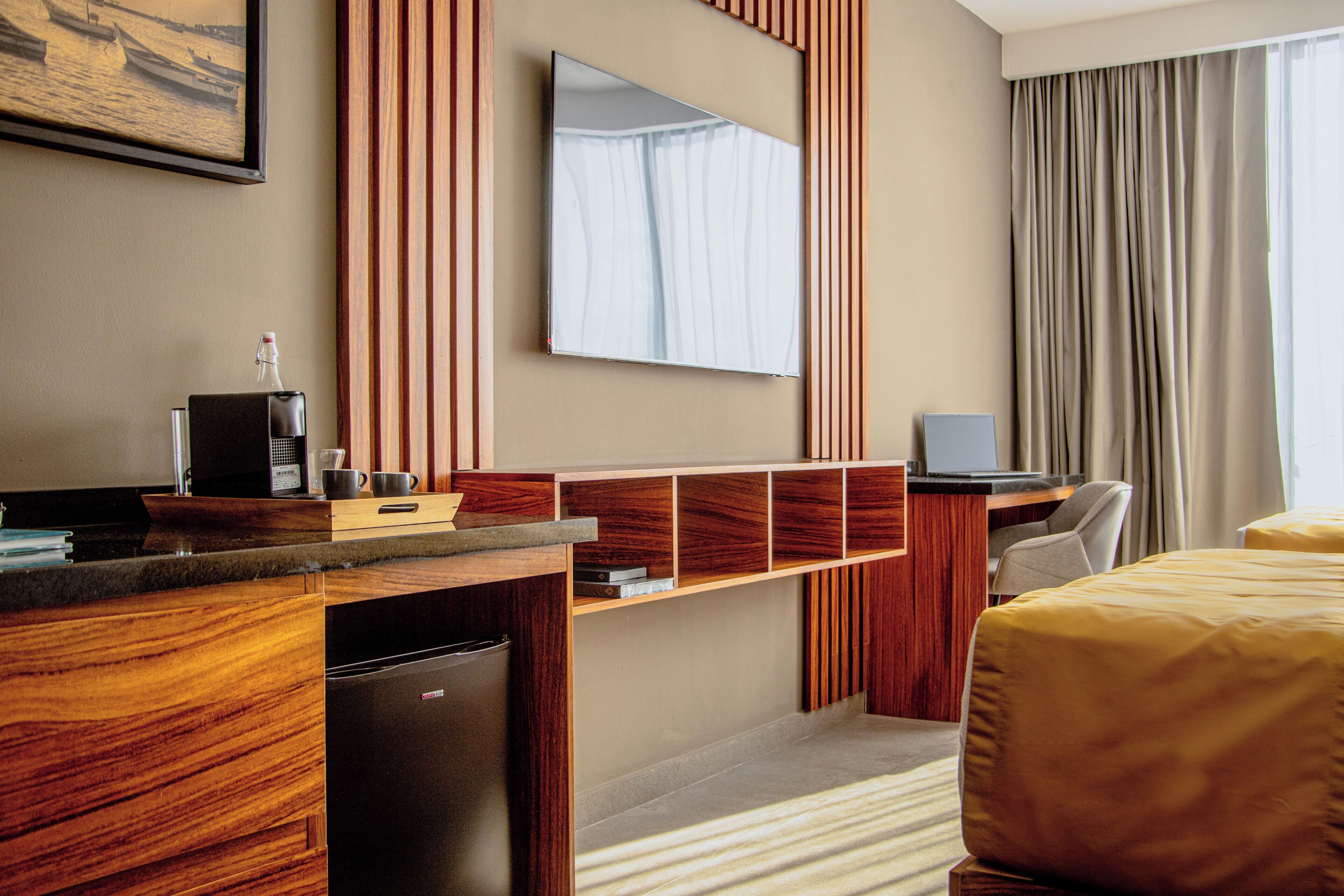 Une chambre d’hôtel avec un bureau en bois, un lit, une télévision et une fenêtre avec des rideaux.