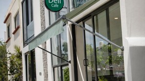 A building with a large glass storefront, a green awning, and a sign that reads 'Deli Cafe.' - LF Hotel Boutique (Playa del Carmen)