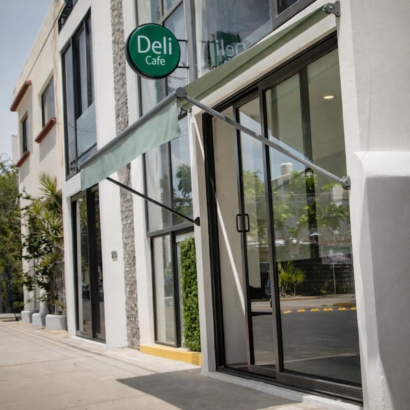 A building with a large glass storefront, a green awning, and a sign that reads 'Deli Cafe.'