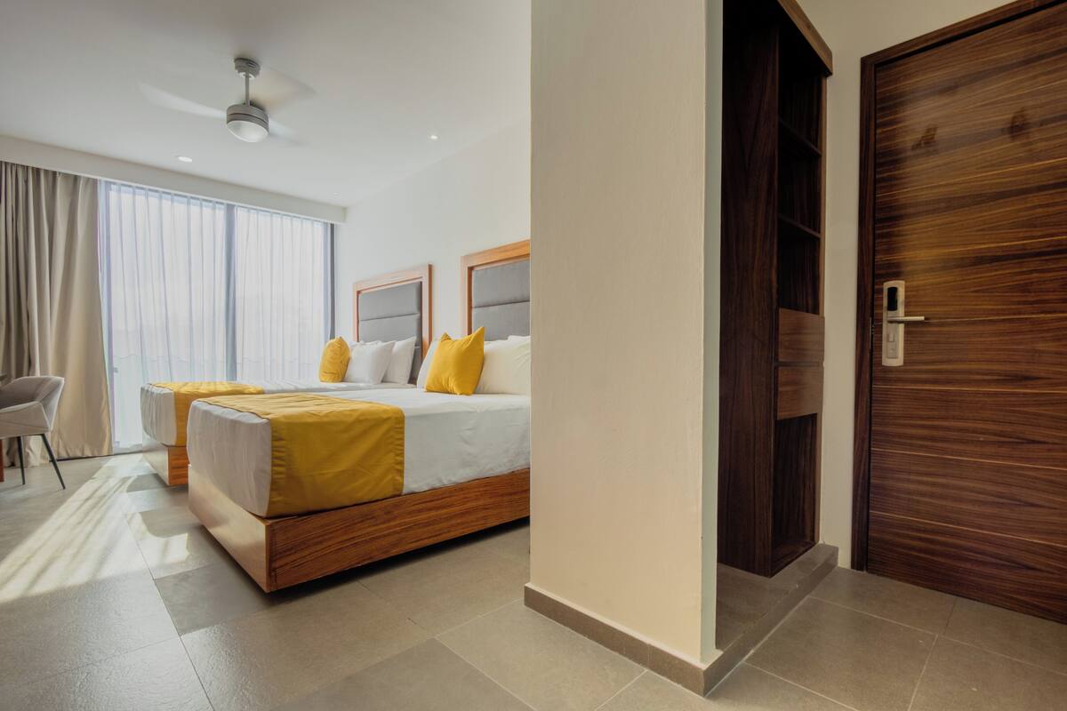 A hotel room with a large bed, two bedside tables, a chair, and a wardrobe.