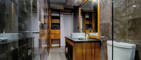 A modern bathroom with a glass shower enclosure, a wooden vanity, a white toilet, and a large mirror.