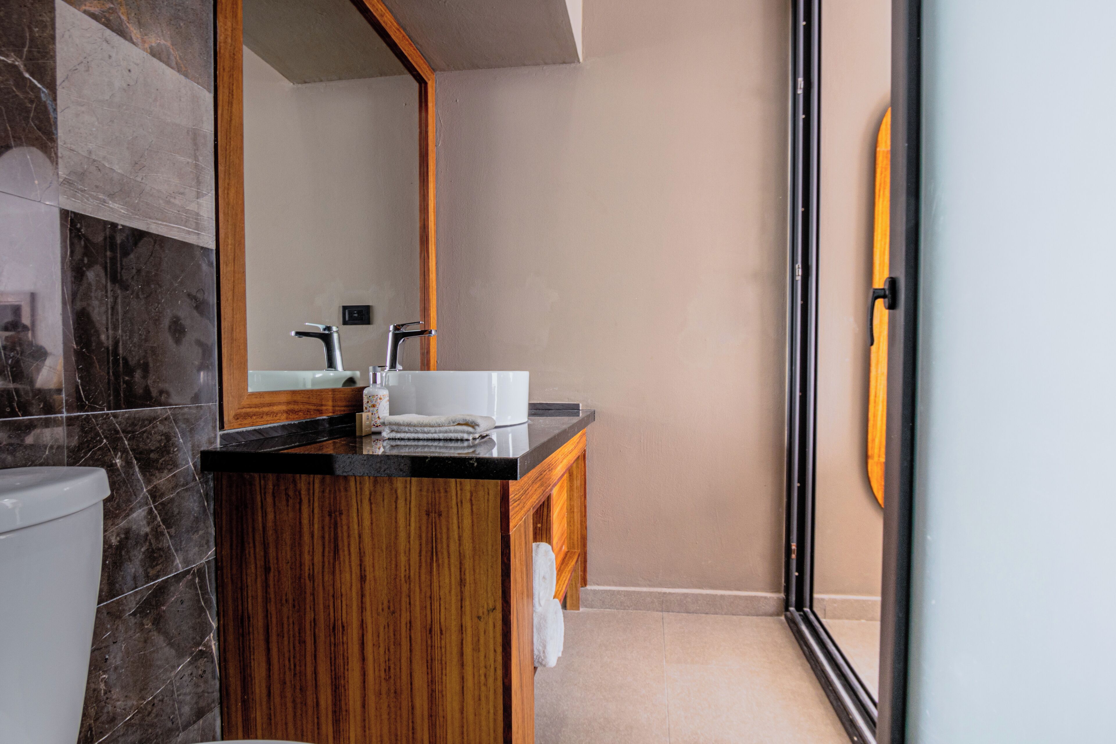 Ein modernes Badezimmer mit einem Holzbadezimmer-Möbelstück, einem weißen Waschbecken und einem großen Spiegel.