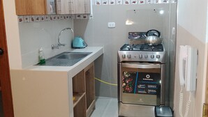 Une cuisine compacte équipée d’une cuisinière à gaz, d’une bouilloire et d’un téléphone intégré.