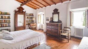 A bedroom with a wooden ceiling, a large bed, a dresser, a chair, a bookshelf, and a window. - Amazing home in Firenze (Firenze)