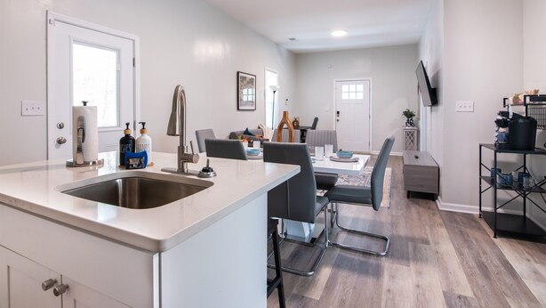 A modern kitchen with a central island, dining area with chairs, and a TV mounted on the wall. - Magic City Manor: Groups/Driveway/Game Room/Wifi (Birmingham)