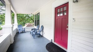 A porch with a red door, two blue chairs, and a black doormat. - Magic City Manor: Groups/Driveway/Game Room/Wifi (Birmingham)