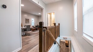 A modern home interior with a wooden staircase, a dining area, and a living room. - Magic City Manor: Groups/Driveway/Game Room/Wifi (Birmingham)