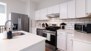 A modern kitchen with white cabinetry, stainless steel appliances, and a tiled backsplash. - Magic City Manor: Groups/Driveway/Game Room/Wifi (Birmingham)