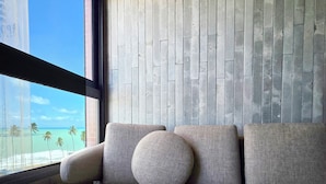 A modern interior with a grey sofa, a round pillow, and a wooden ceiling. - Apê Design Vista Mar, Piscina, Hidro e Academia (Maceió)