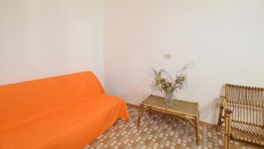 Una habitación con un sofá, una mesita con un florero y una silla.