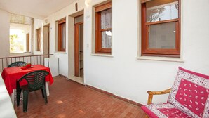 Una habitación con una mesa y sillas rojas, un banco de madera y una ventana con vistas.