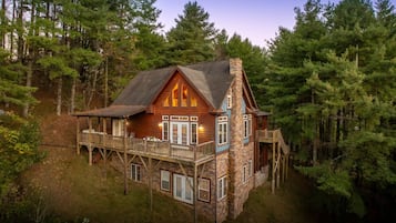 A cabin with a stone exterior, wooden deck, and multiple windows.