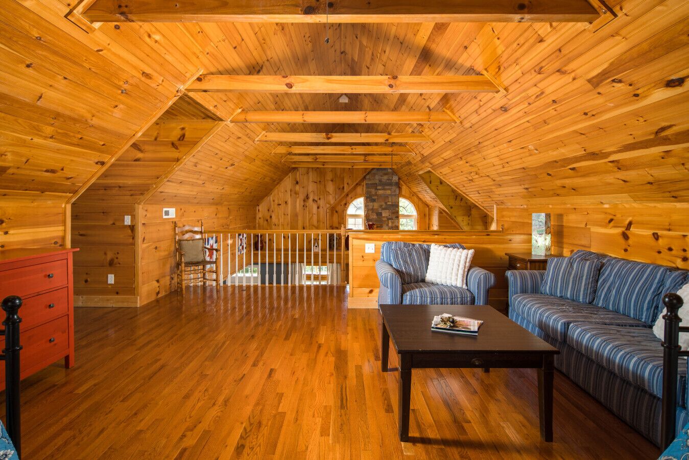 L’intérieur d’une cabane en rondins, avec un plancher en bois, un canapé, une table et une commode rouge.